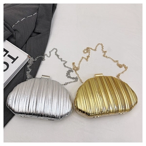 Close-up of pleated metallic shell-shaped clutch bags in gold and silver with chain straps