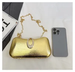 Size comparison of a gold hardshell evening clutch with rhinestone buckle and chain
