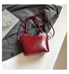 Detail of burgundy bucket bag with glossy pleated leather and silver hardware accents