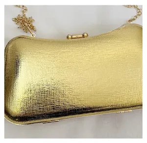 Detail of gold evening clutch bag with fine ripple texture and metallic chain strap