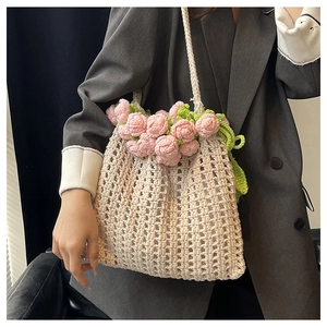 Detail of hand-crocheted cream tote bag with pink rose accents on a grey blazer outfit