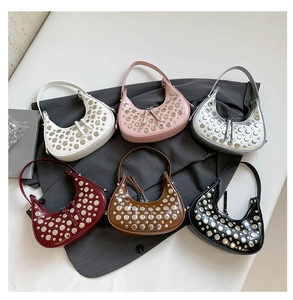 Detailed overhead view of studded bucket bags in multiple colors on a grey fabric backdrop