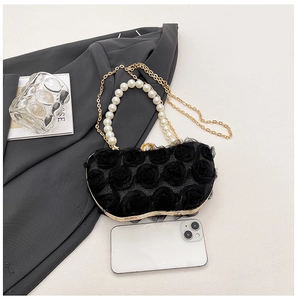 Detail of black 3D flower evening bag with elegant pearl handle and gold chain strap