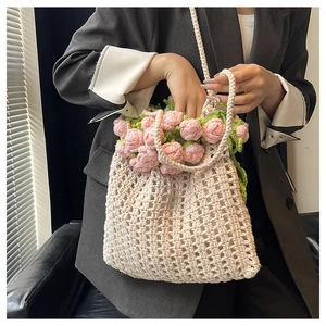 Detail of hand-crocheted cream tote bag with 3D pink tulip flowers and green leaves