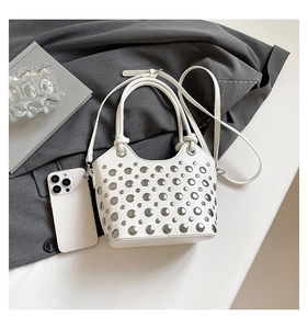 Close-up of a white bucket bag with silver studs, showing handle and strap details