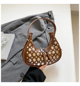 Detail of a brown moon bag with metallic silver rivets and smooth leather texture