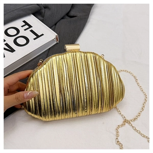 Detail of gold pleated clutch bag with metallic texture and elegant chain strap