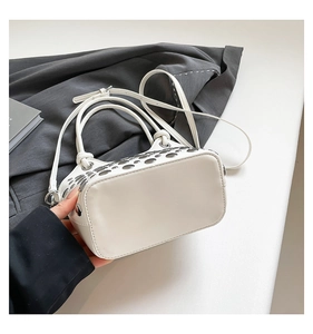Close-up of white bucket bag featuring silver metal eyelets and decorative studs