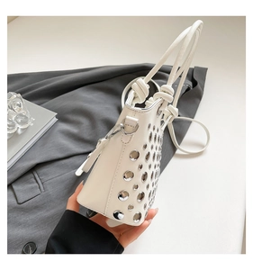 Close-up of ivory bucket bag featuring silver ring studs and leather cord handle