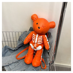 Detail of orange bear backpack featuring white bone print and cross-stitched eyes