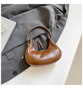 Close-up of brown glossy leather hobo bag with dual silver zippers and long pull tabs