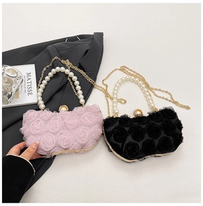 Detail of elegant evening bag with 3D fabric roses, pearl handle and gold chain strap