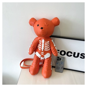 Macro detail of orange bear bag with white skeletal embroidery and cross stitch details