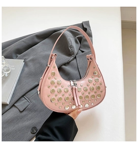 Close-up of pink crescent underarm bag featuring decorative silver metal studs and dual zippers