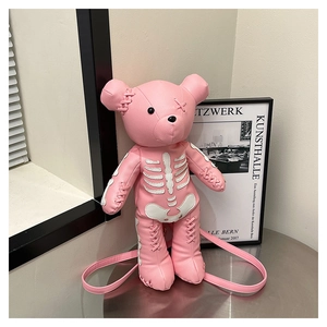 Pink cartoon bear backpack with bone print and cross-stitching detail on a metal table