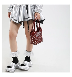 Detail of burgundy bucket bag featuring silver punk studs and unique knot handles