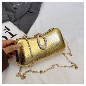 Detail of a gold evening clutch featuring a rhinestone U-buckle and brushed metal texture