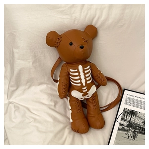 Detail of a brown bear-shaped backpack with white skeletal embroidery and stitching