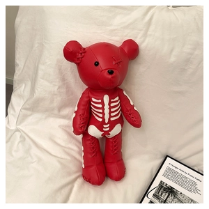 Artistic close-up of a red leather skull teddy bear backpack beside a vintage book