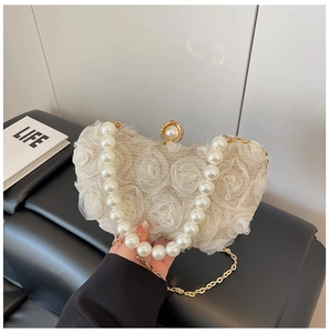Detail of floral lace texture on beige evening bag with pearl handle and gold chain