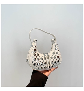 Close-up of white leather hobo bag featuring silver rivets and dual zipper closure