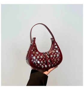 Detailed macro view of deep red hobo bag featuring polished silver metal punk rivets