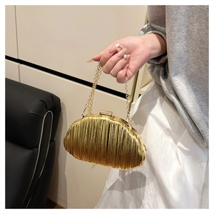 Detailed view of luxury gold pleated shell evening clutch with metallic chain strap