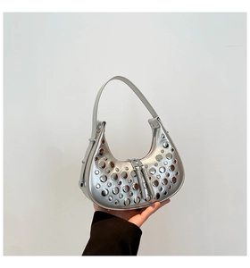 Detailed close-up of silver crescent hobo bag featuring decorative metal rivets and zippers