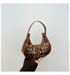 Detail of brown crescent bag featuring metallic silver studs and double zipper design