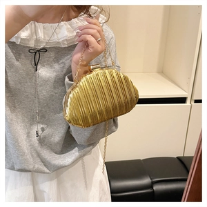 Macro view of gold pleated evening clutch bag with vertical metallic texture and chain