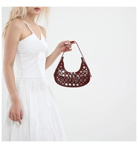 Detailed macro view of dark red leather crescent bag with silver metallic rivets