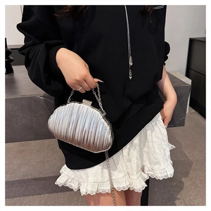 Close-up of a silver shell-shaped evening clutch with vertical pleated texture and chain