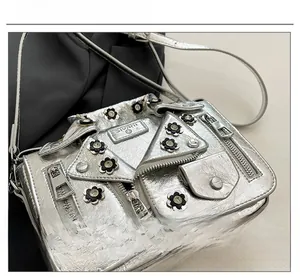 Close-up of silver jacket-shaped crossbody bag with zipper details and floral appliqués