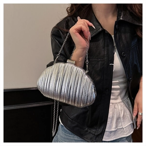 Detailed view of silver shell-shaped evening clutch bag with pleated texture and chain