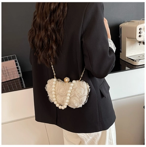 Detail of cream lace flower evening bag with pearl handle and gold chain strap
