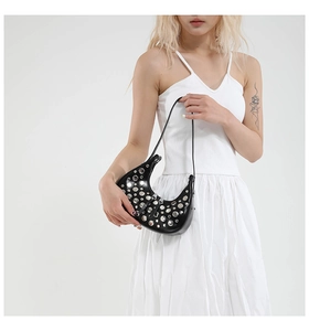 Detail view of black crescent underarm bag featuring silver rivets and zip closure