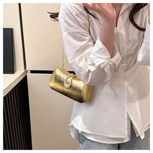 Detail of gold hard-shell evening clutch with rhinestone buckle and fine chain strap