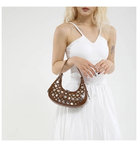 Detail of brown leather crescent bag featuring silver studs and a smooth zipper closure