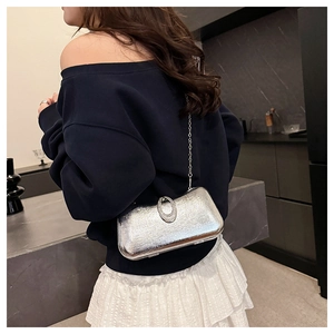 Detail of silver metallic evening clutch bag with rhinestone buckle and chain strap