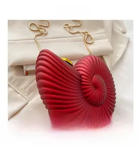 Close-up of matte red acrylic shell bag with spiral texture and golden metal chain