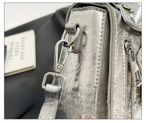 Macro shot of silver motorcycle jacket bag showing metal snap hook and zipper details