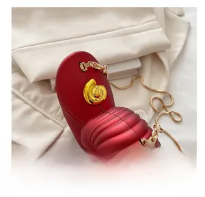 Macro view of snail-shaped acrylic clutch bag with red matte finish and gold chain strap