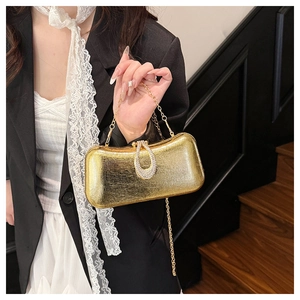 Close-up of golden metallic clutch bag featuring a crystal horseshoe buckle and gold chain