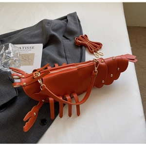 Detail view of orange lobster-shaped bag with gold studs and silver zipper closure