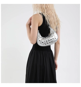 Detail of silver crescent armpit bag with metallic studs on a minimalist model