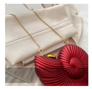 Detailed view of red nautilus acrylic clutch with gold snake chain and hardware accents