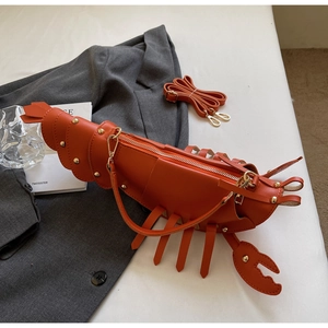 Detail of lobster-shaped crossbody bag with orange PU leather and gold rivet accents