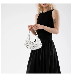 Close-up of white crescent shoulder bag featuring industrial metal ring hollow-out detail