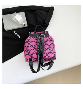Detail of pink snake skin print backpack with black faux leather straps and silver buckles