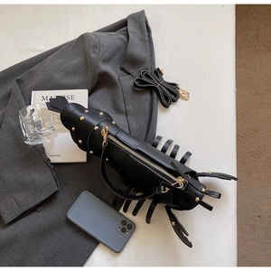 Detail of creative black lobster crossbody bag with gold rivets and metallic zipper